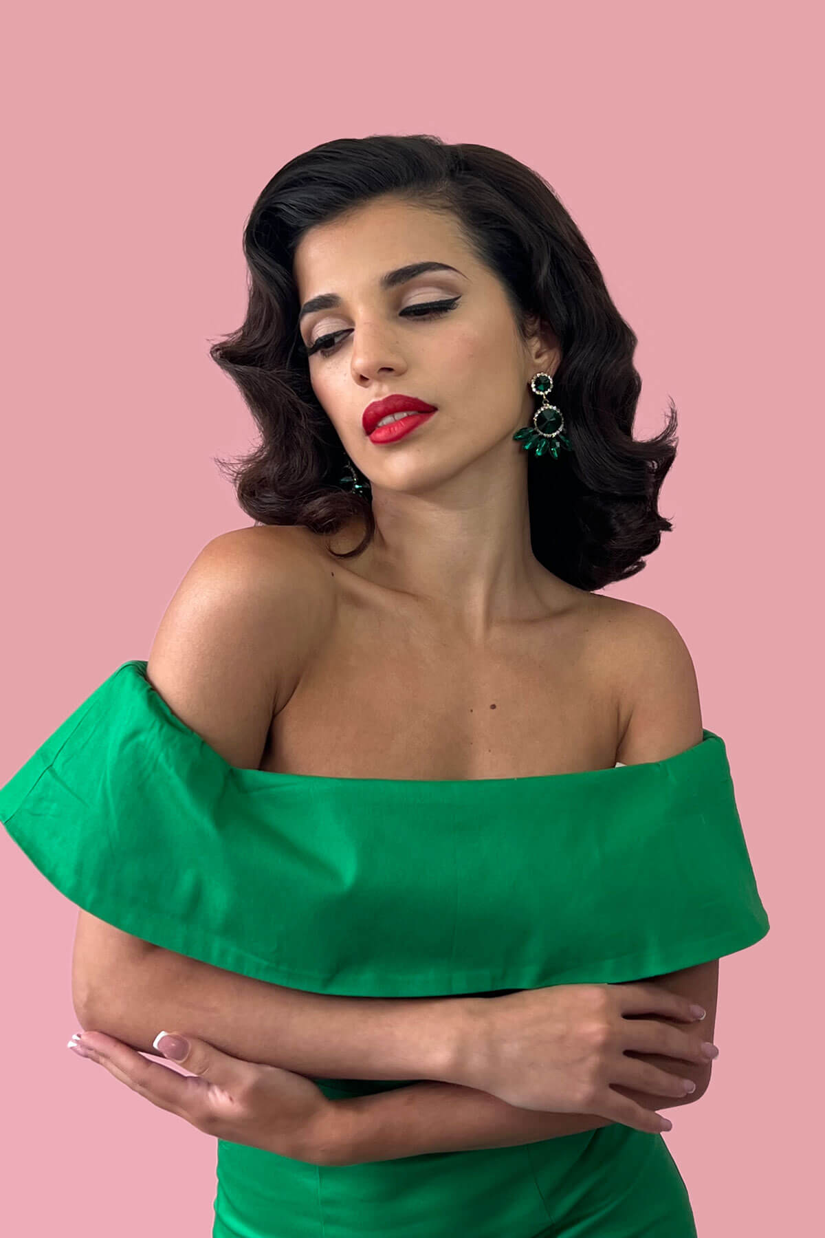 Woman wearing a green off-shoulder dress against a pink background