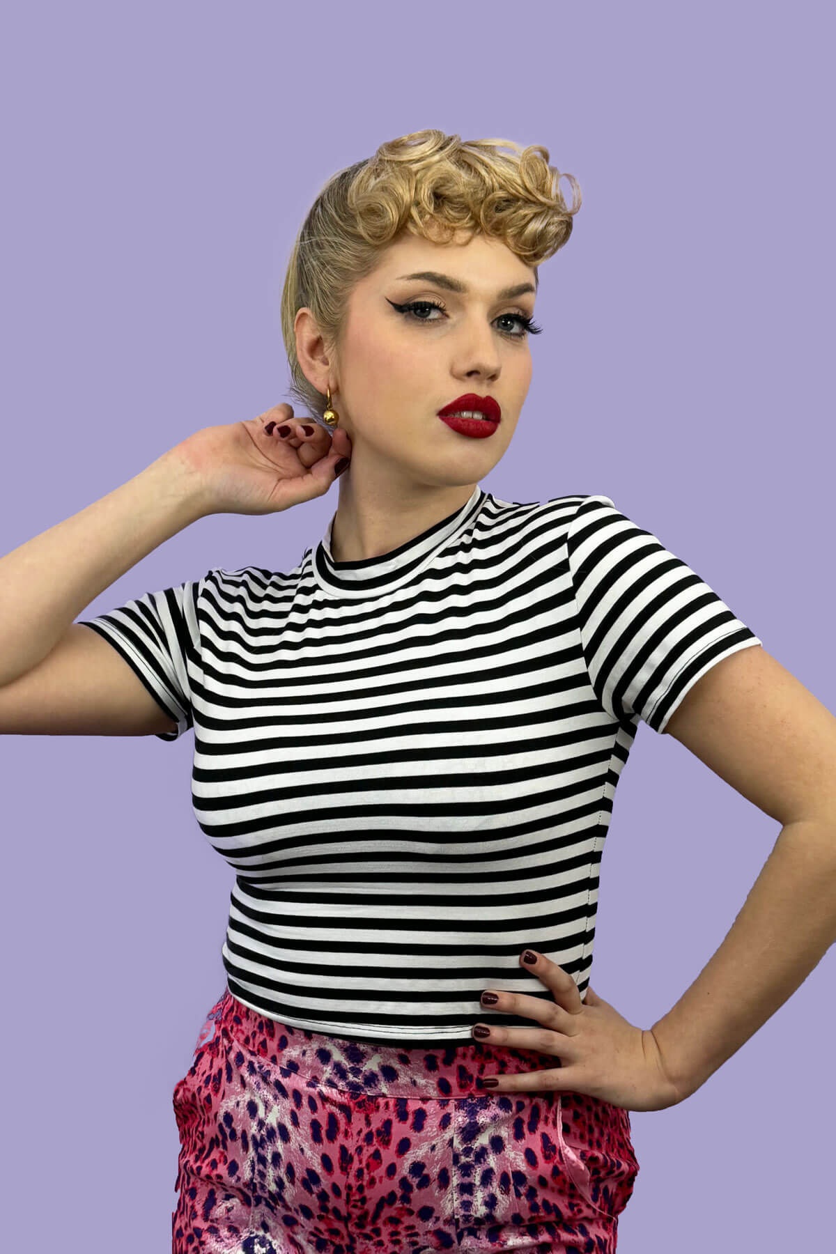 Woman wearing a black and white striped shirt with colorful pants against a purple background. Curly 1940s style clip-in fringe hairpiece/clip-in bangs: Bunny chestnut brown 8