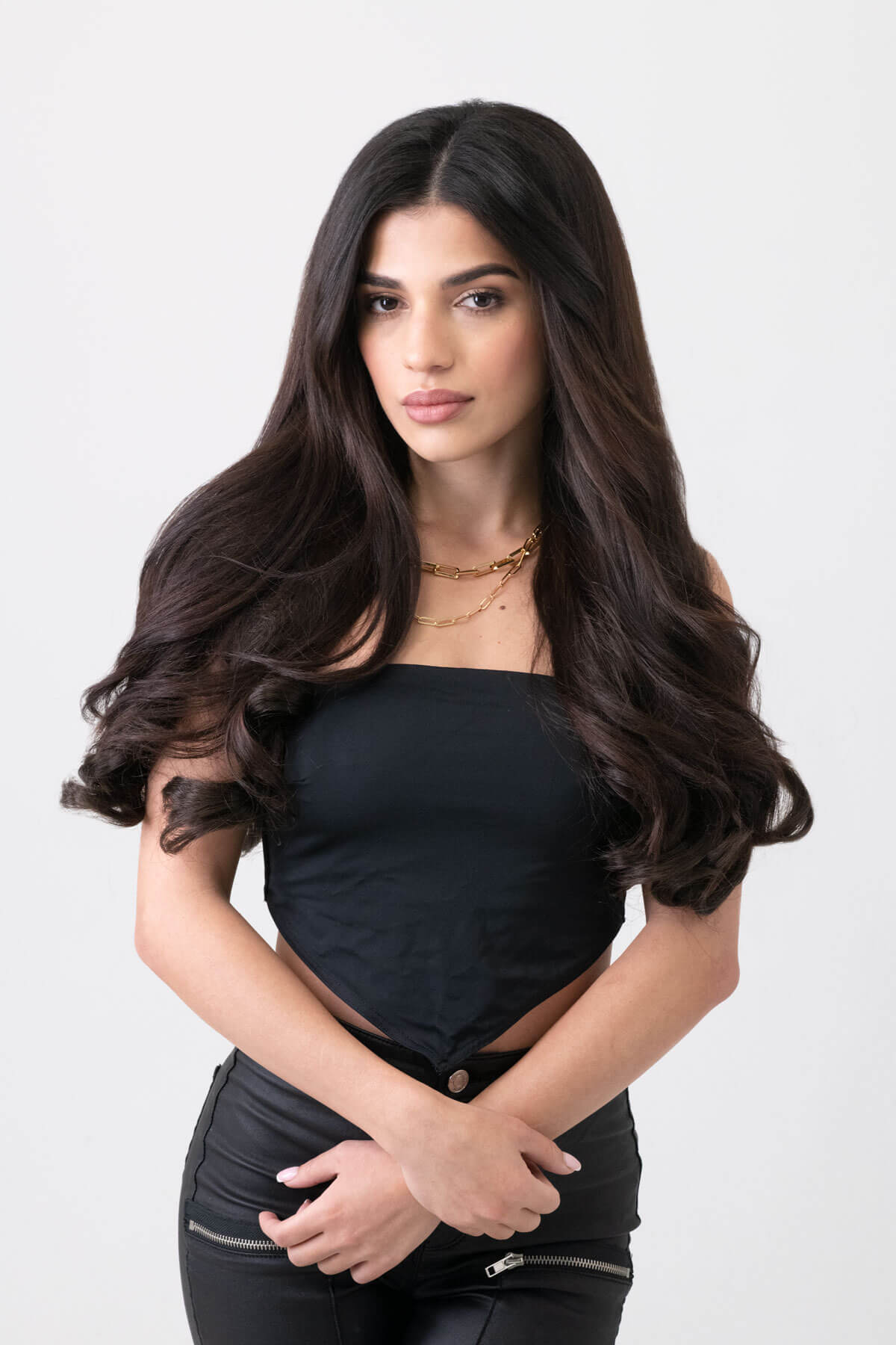Woman with long dark hair wearing a black outfit on a white background. 5 piece synthetic hair extension set, 18 inches long, 260g 1b