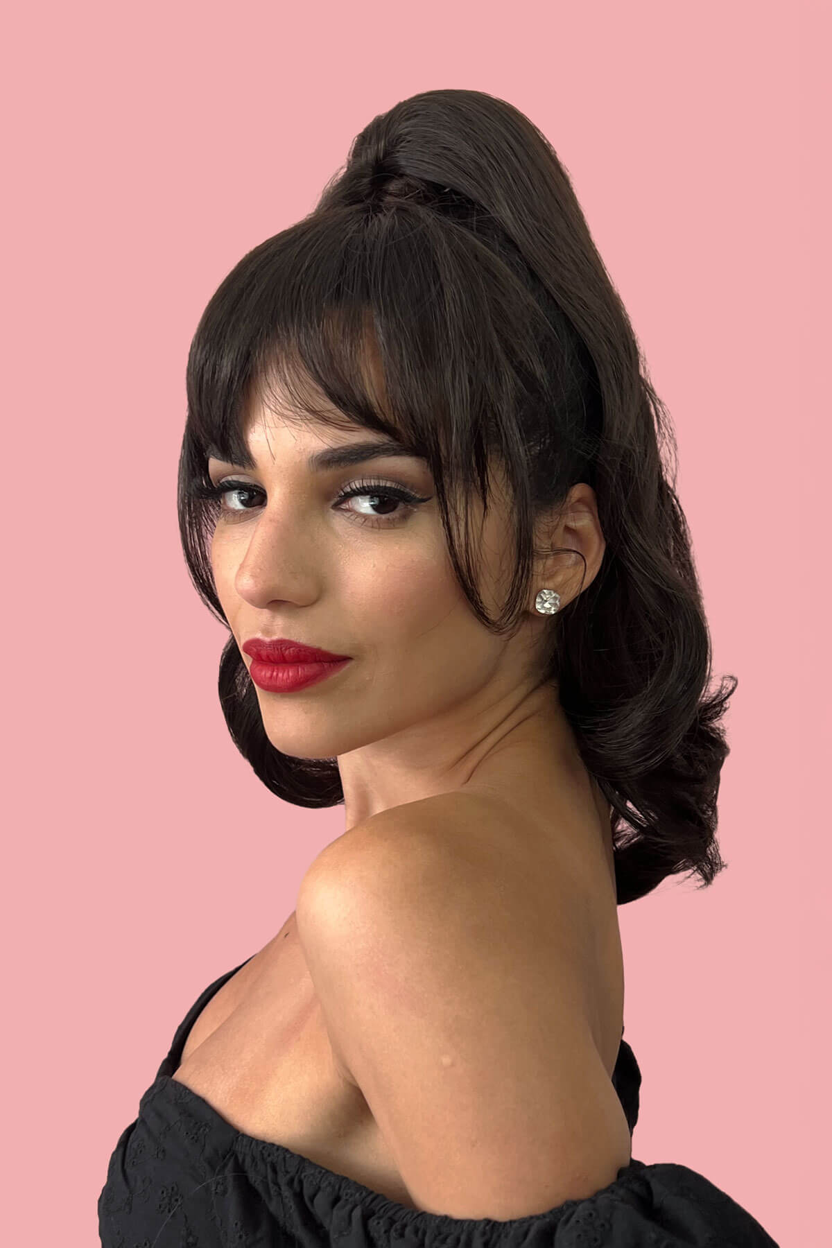 Woman with styled hair and red lipstick against a pink background. Clip in fringe hairpiece/clip-in bangs, gently feathered with face framing whisps: Delia blonde 24H613