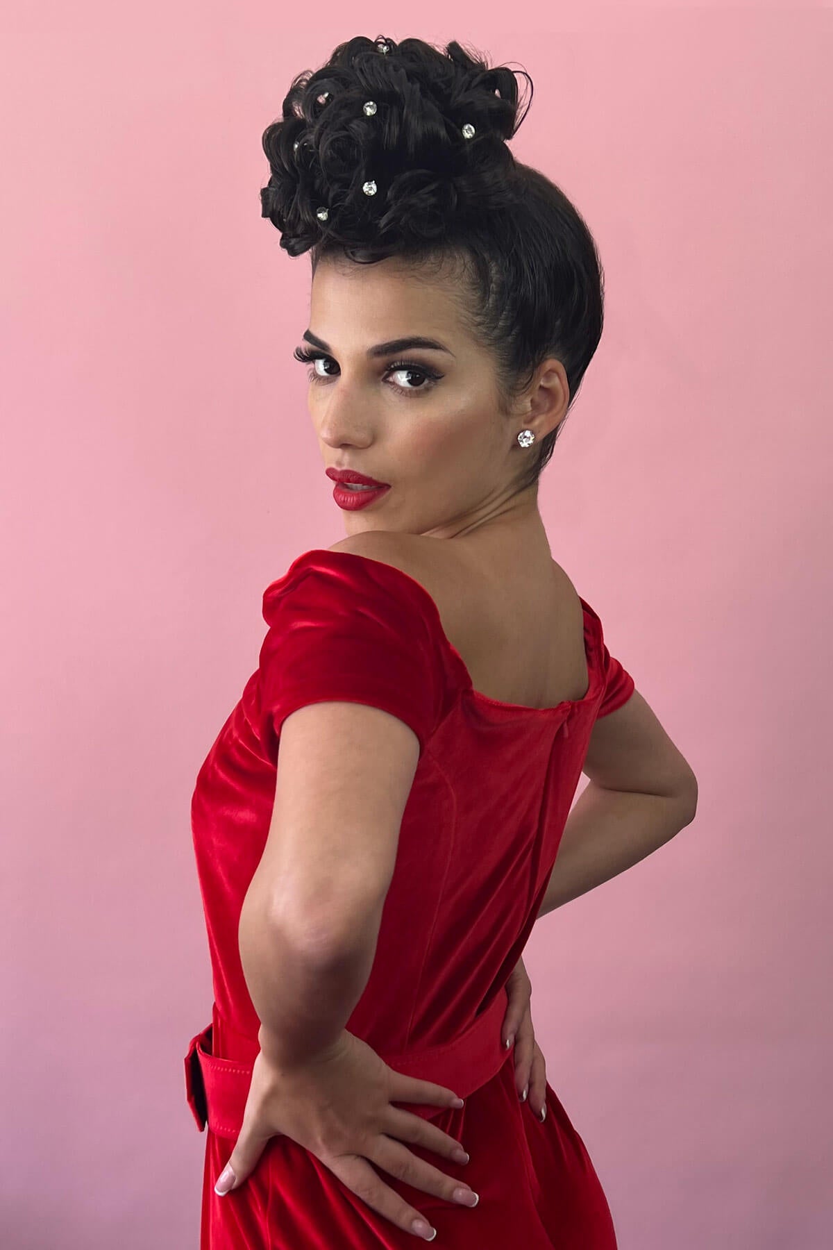 Woman with a hair poodle in a red dress with a pink background. Hair poodle clip-in hairpiece bun vintage style 1950s: Lucille dark chocolate brown 6