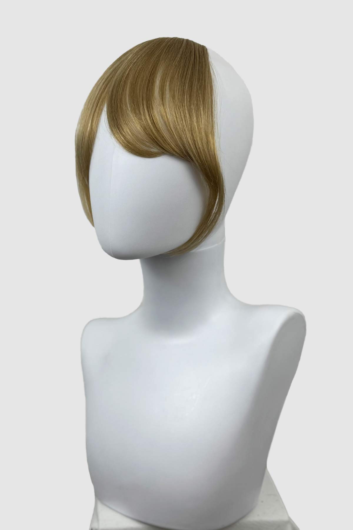 Mannequin head with a blonde wig on a white background. Clip in fringe hairpiece/clip-in curtain bangs, with long, face framing wisps: Sabrina blonde 24H613