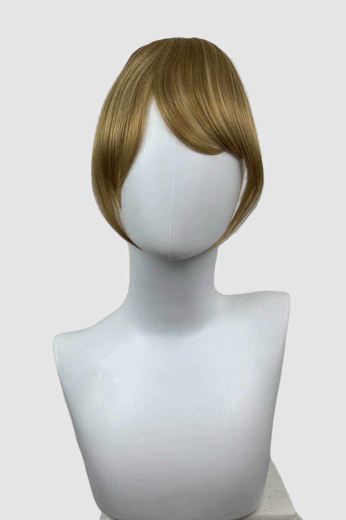 Blonde wig on a mannequin head against a white background. Clip in fringe hairpiece/clip-in curtain bangs, with long, face framing wisps: Sabrina blonde 24H613