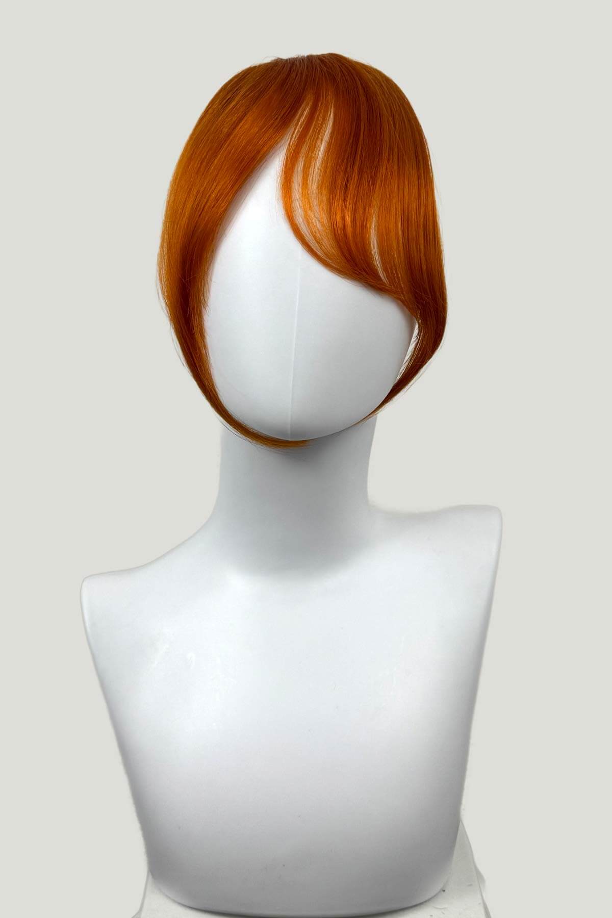 Mannequin head with a ginger hairpiece on a white background. Clip in fringe hairpiece/clip-in curtain bangs, with long, face framing wisps: Sabrina ginger