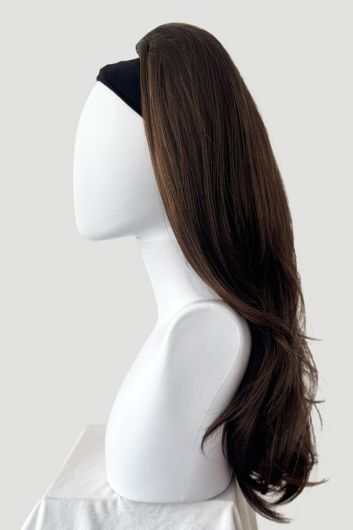 Mannequin head with a long brown wig on a white background. 1960s style hair, high crown long straight and layered half wig: Juliette brown with blonde highlights 8H27