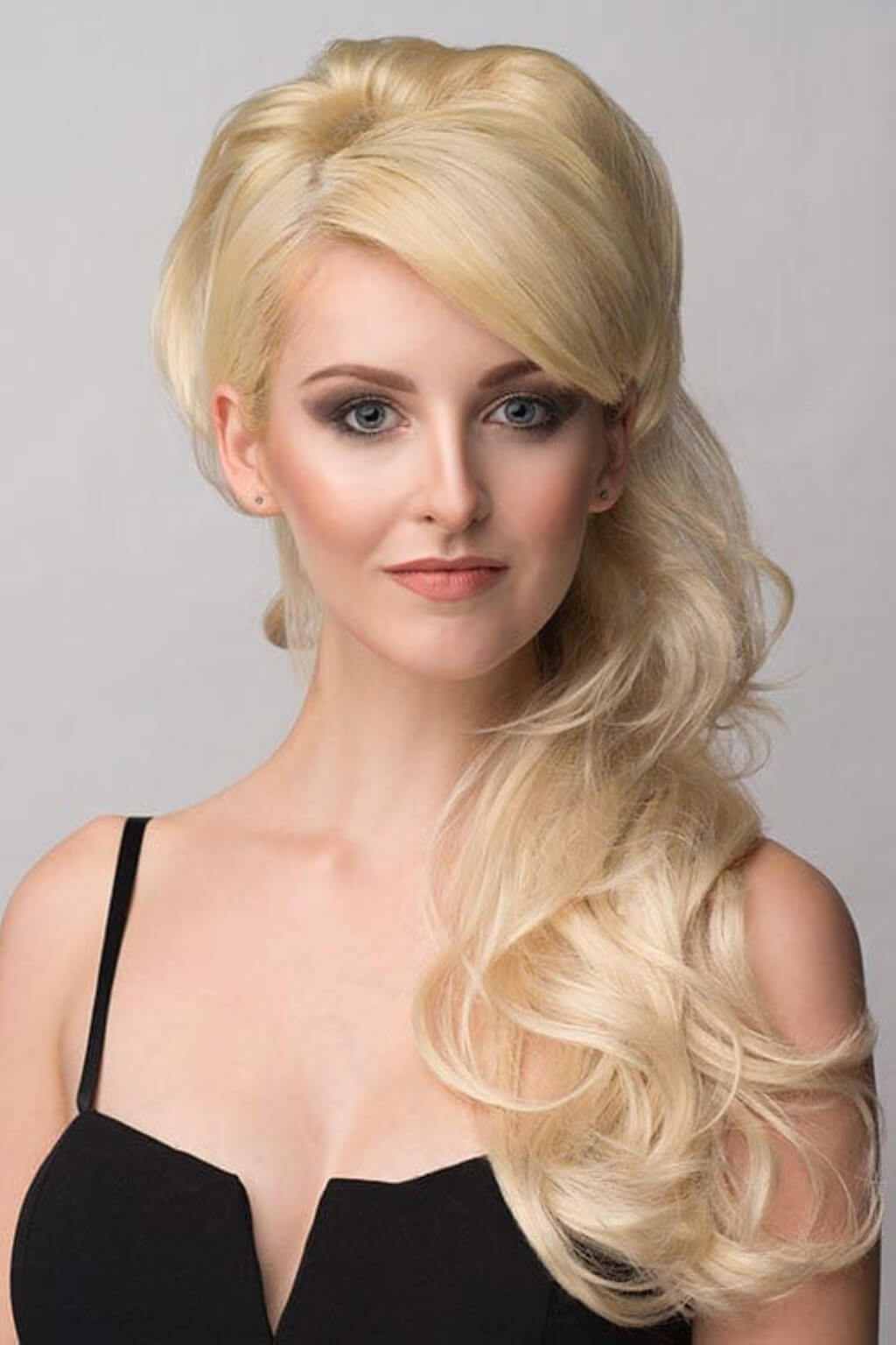 Woman with styled blonde hair against a plain background. Double volume hairpiece extension: Naomi