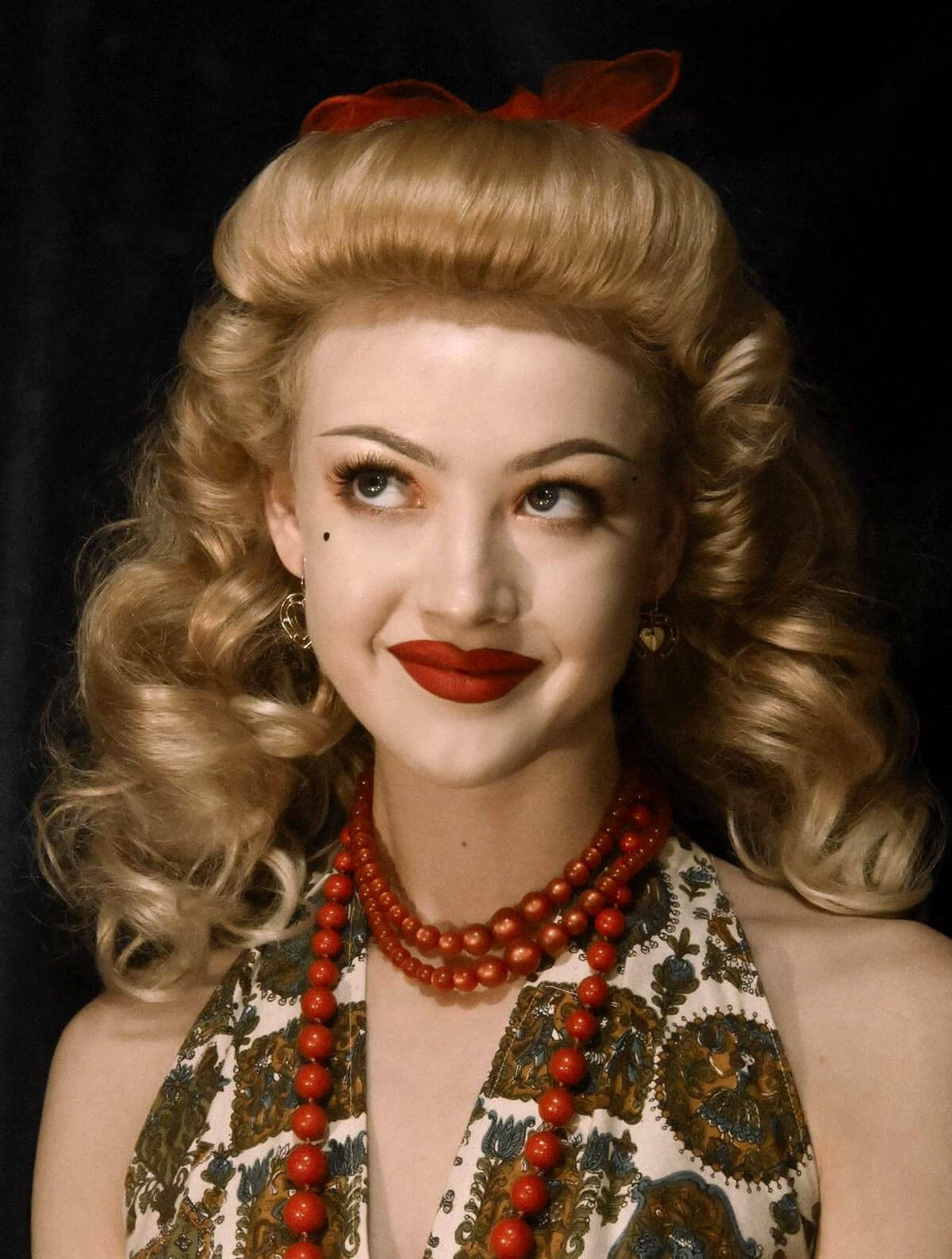 Woman with vintage hairstyle and makeup, wearing a patterned dress and red jewelry against a dark background. Bumper bangs pack - vintage 40s 50s fringe roll: Lena blonde 24H613