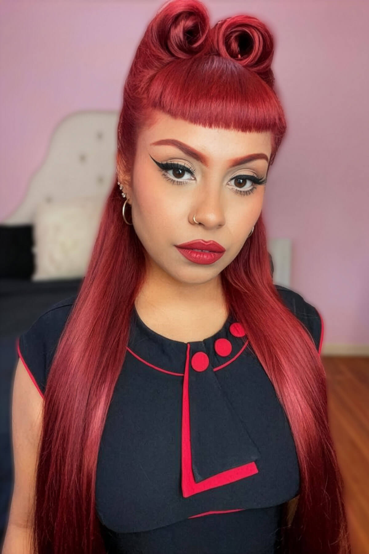 Woman with red hair styled in two victory rolls wearing a black outfit with red accents. Victory roll kit: Ingrid - cherry red
