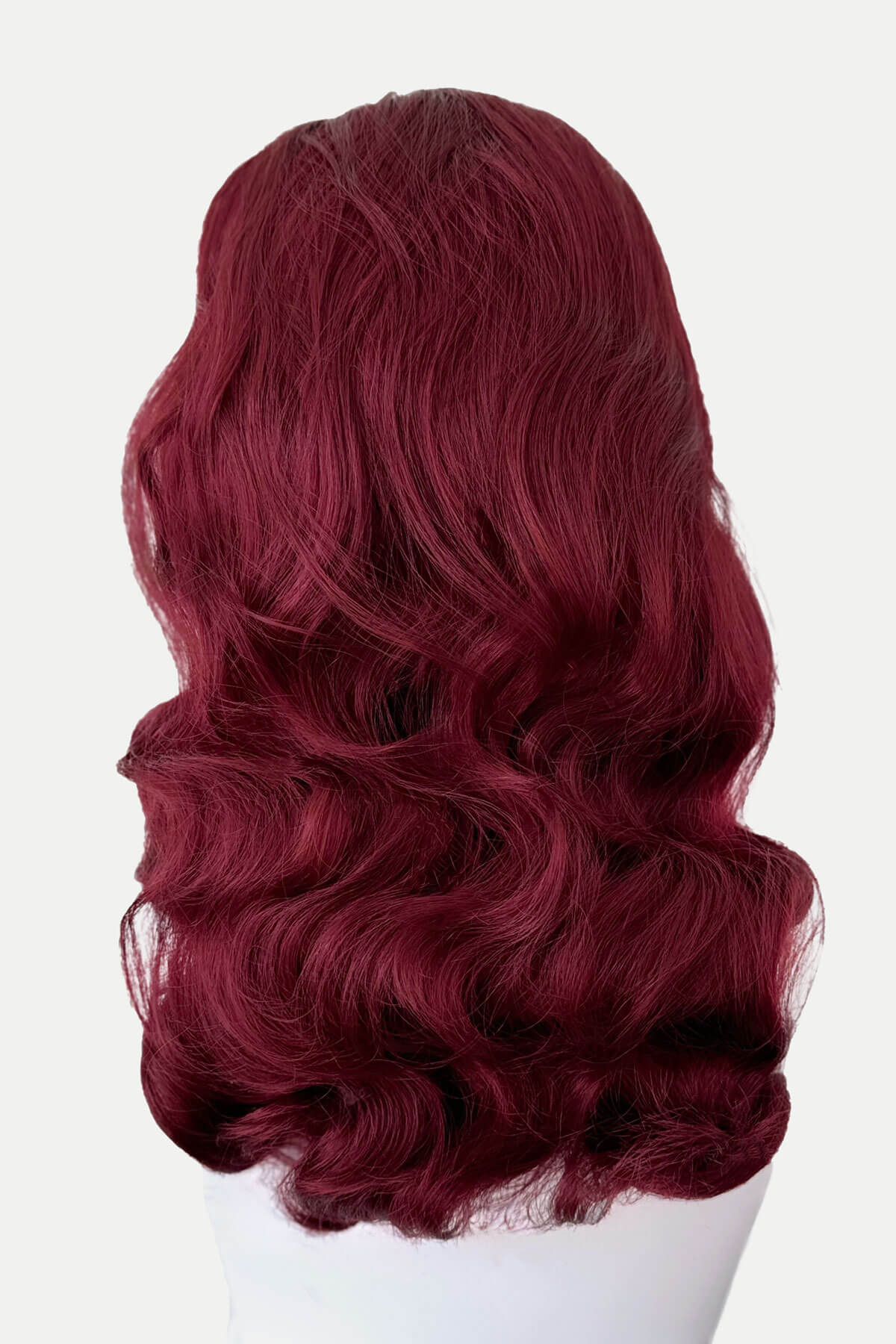 Red wig on a white mannequin head against a white background. 1950s style half wig hairpiece with beautiful waves: Morgana red 39