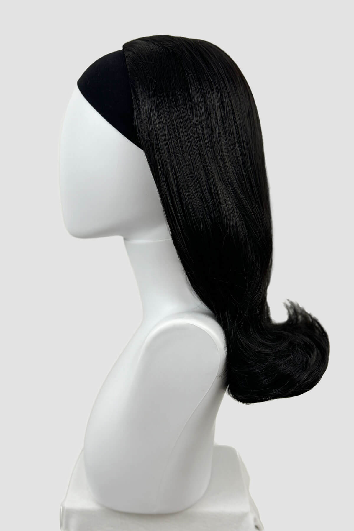 Black wig on a white mannequin head against a light gray background. 1960s half wig hairpiece, flicked, hair flip: Philippa black 1B