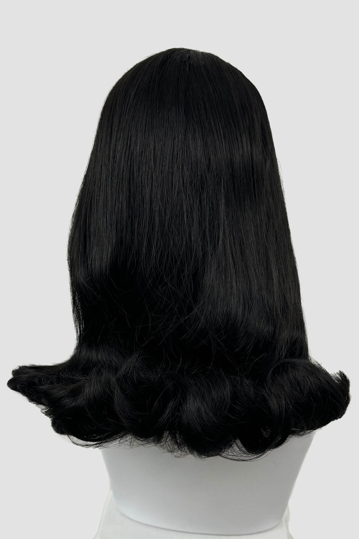 Black wig on a white mannequin head against a light gray background. 1960s half wig hairpiece, flicked, hair flip: Philippa black 1B