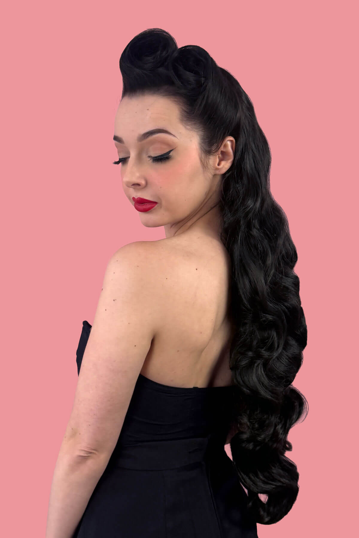 Woman with long, wavy black hair on a pink background. Ultra long half wig with hollywood waves. ginger