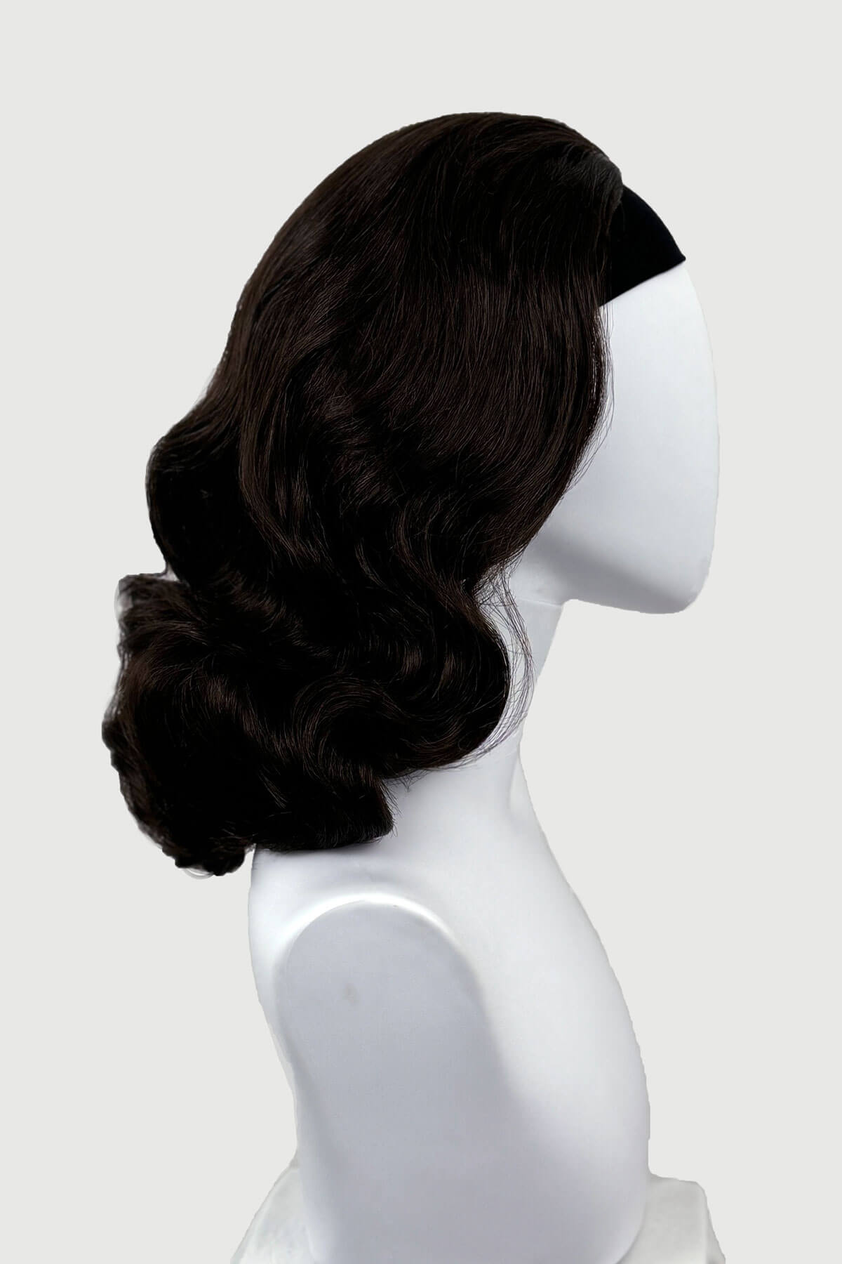Dark chocolate brownwig on a mannequin head against a white background viewed from the side. 1950s style shoulder length half wig hairpiece with beautiful vintage waves: Onyx dark chocolate brown 6