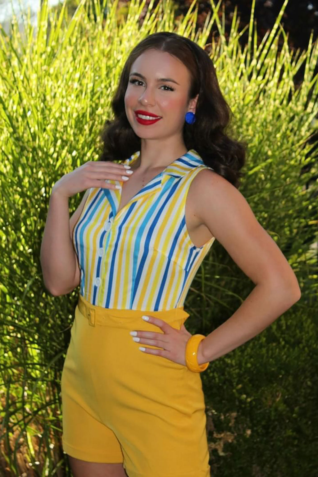 Woman in a yellow and blue striped dress standing in front of green foliage. half wig Onyx1950s style shoulder length half wig hairpiece with beautiful vintage waves: Onyx chestnut brown 8