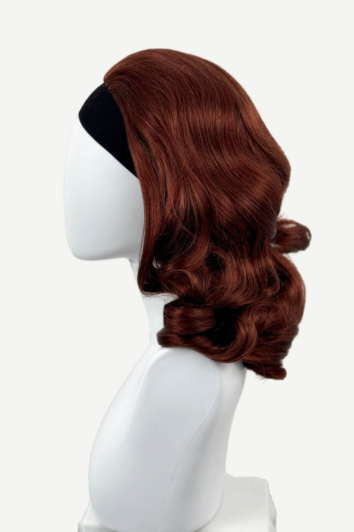 Brown wig on a white mannequin head against a white background, viewed from the side. 1950s style shoulder length half wig hairpiece with beautiful vintage waves: Onyx copper red 130