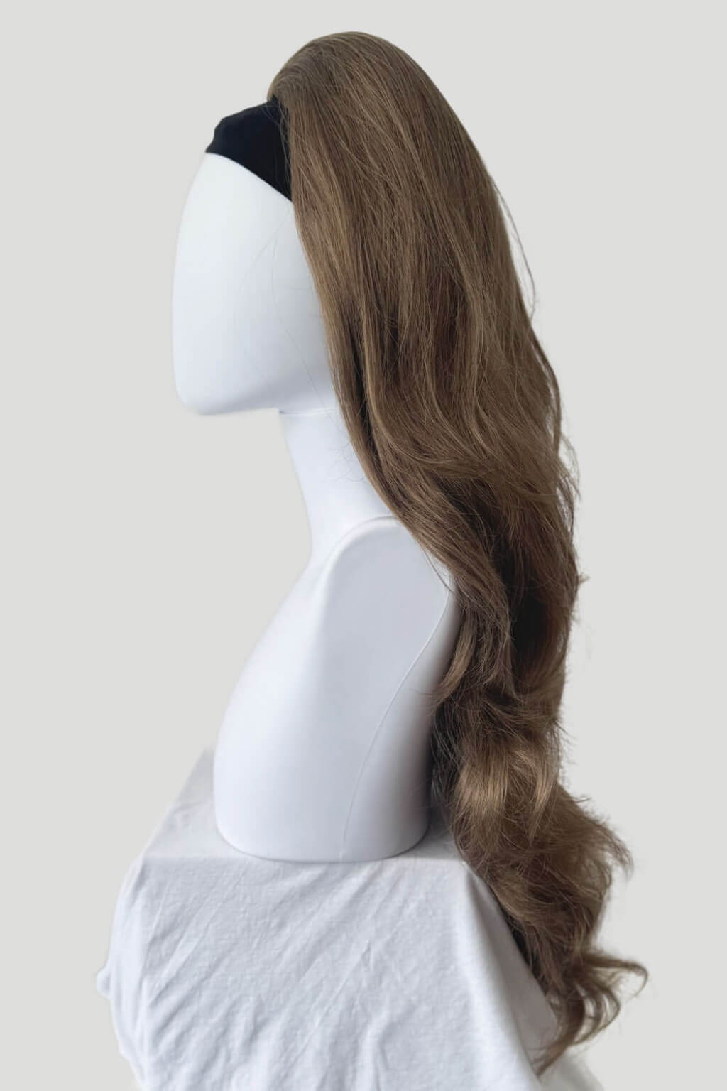 Mannequin head with long brown wig on a plain background. High crown long, wavy half wig and volume ring: Bardot brown 10-16-27
