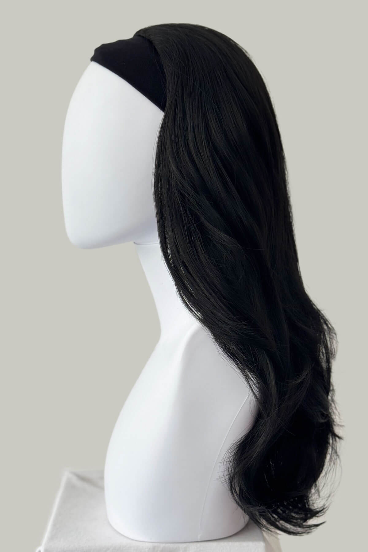 Black wig on a white mannequin head against a plain background. Straight black half wig hairpiece, layered: Cerys