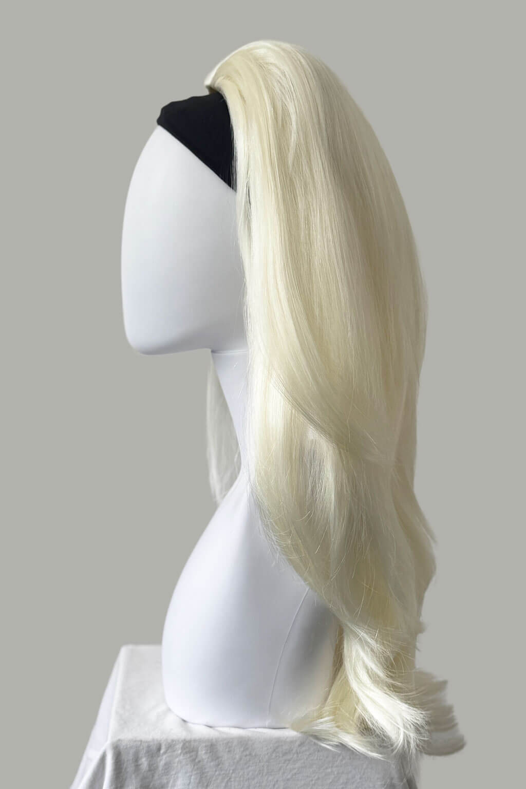Blonde wig on a mannequin head against a plain background. Straight platinum blonde half wig with height booster