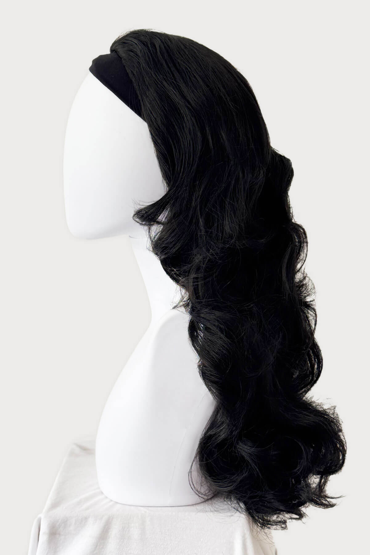 Black wig on a mannequin head against a white background. Curly black half wig hairpiece, long: Vicky