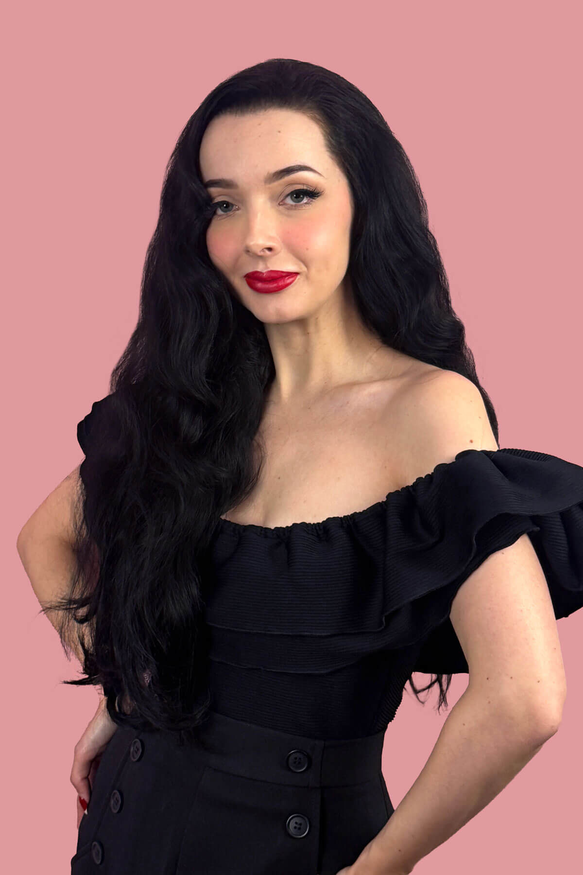 Woman with long black wavy hair and red lipstick posing against a pink background. Black half wig hairpiece (3/4 wig), long layers: Aislynn jet black 1