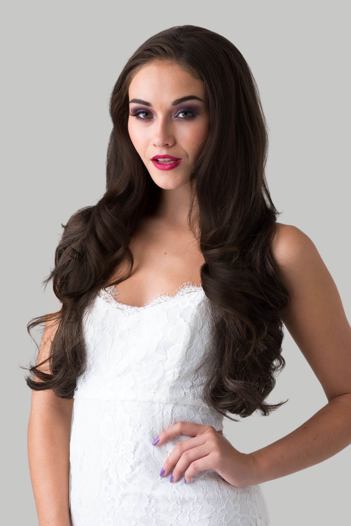 Woman with long brown hair wearing a white dress against a gray background. Brown half wig hairpiece (3/4 wig), layered, wavy: Simone chestnut brown 8