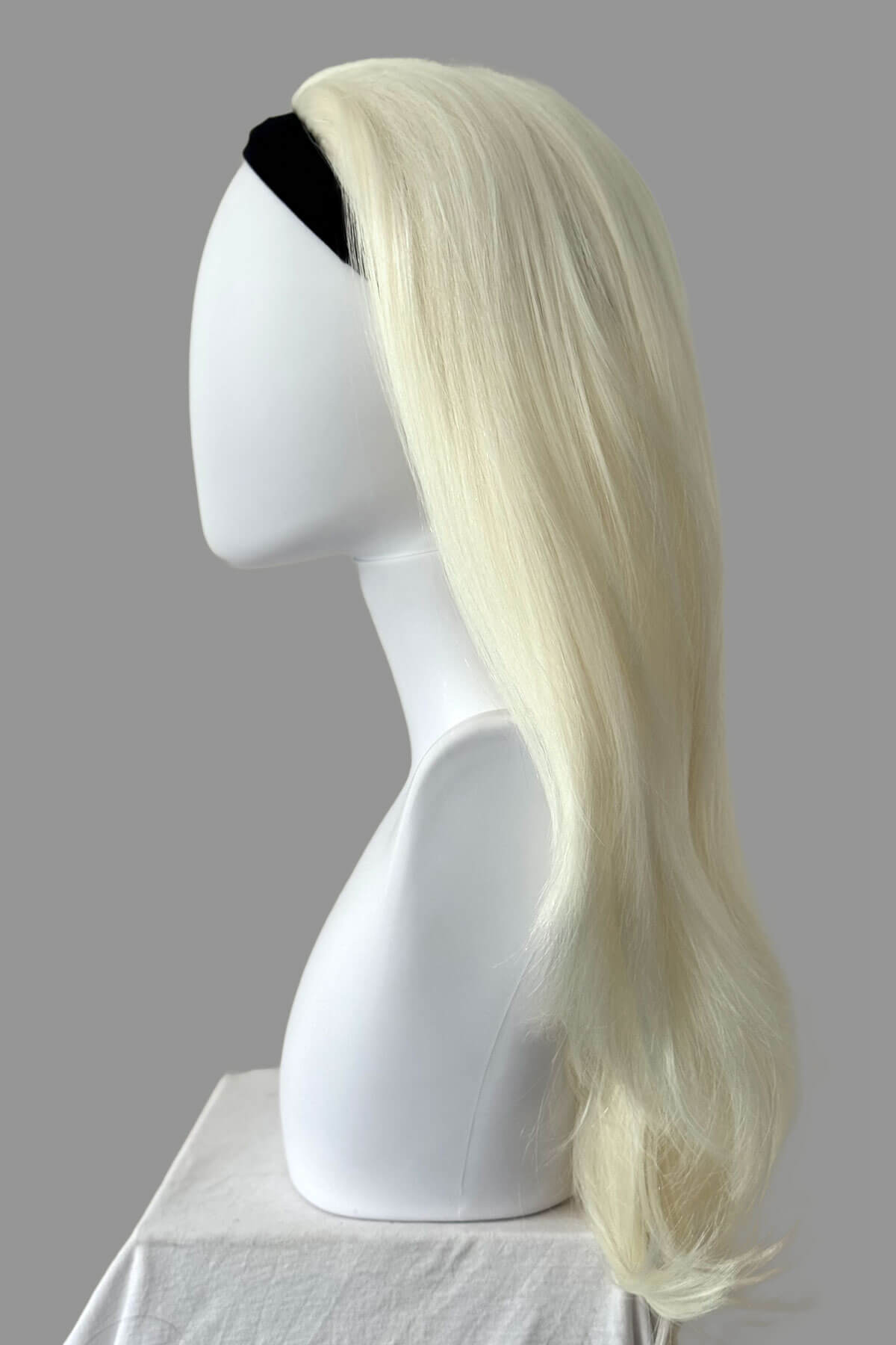 Blonde wig on a mannequin head against a gray background. Platinum blonde half wig hairpiece (3/4 wig), straight: Gwen