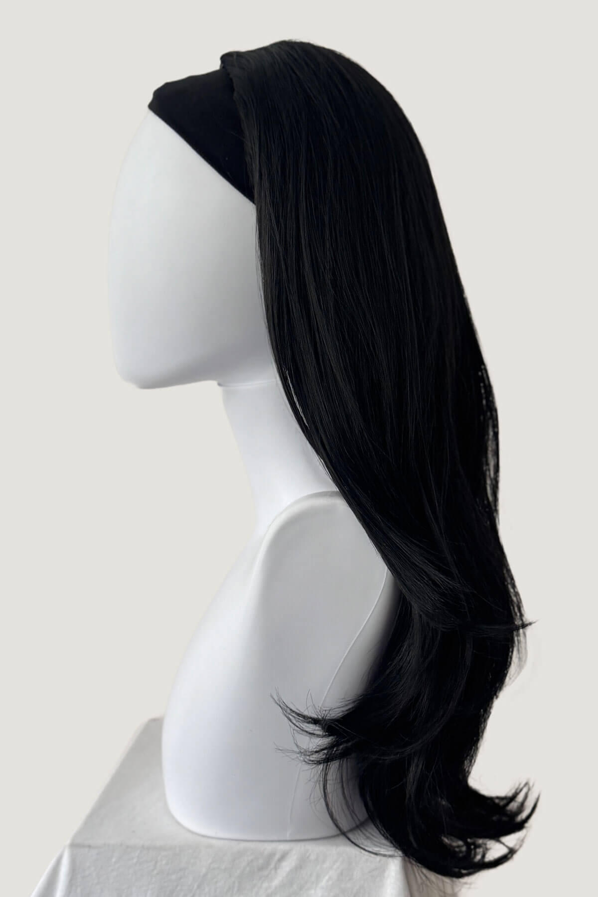 Black wig on a mannequin head against a white background. Straight black hairpiece (3/4 wig), long and layered: Raven