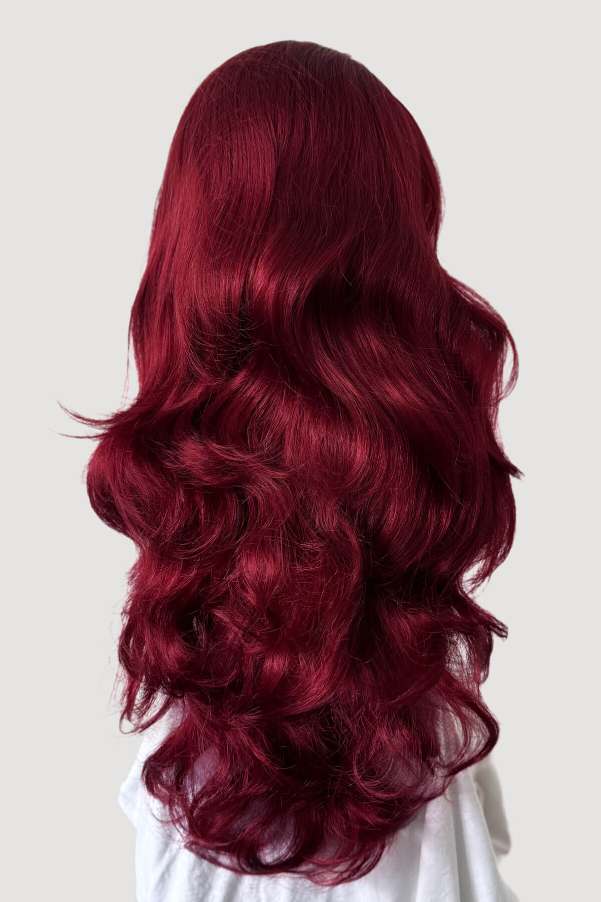 Long, wavy red hair on a plain background. Red half wig (3/4 hairpiece) with long waves: Sasha wine red 39
