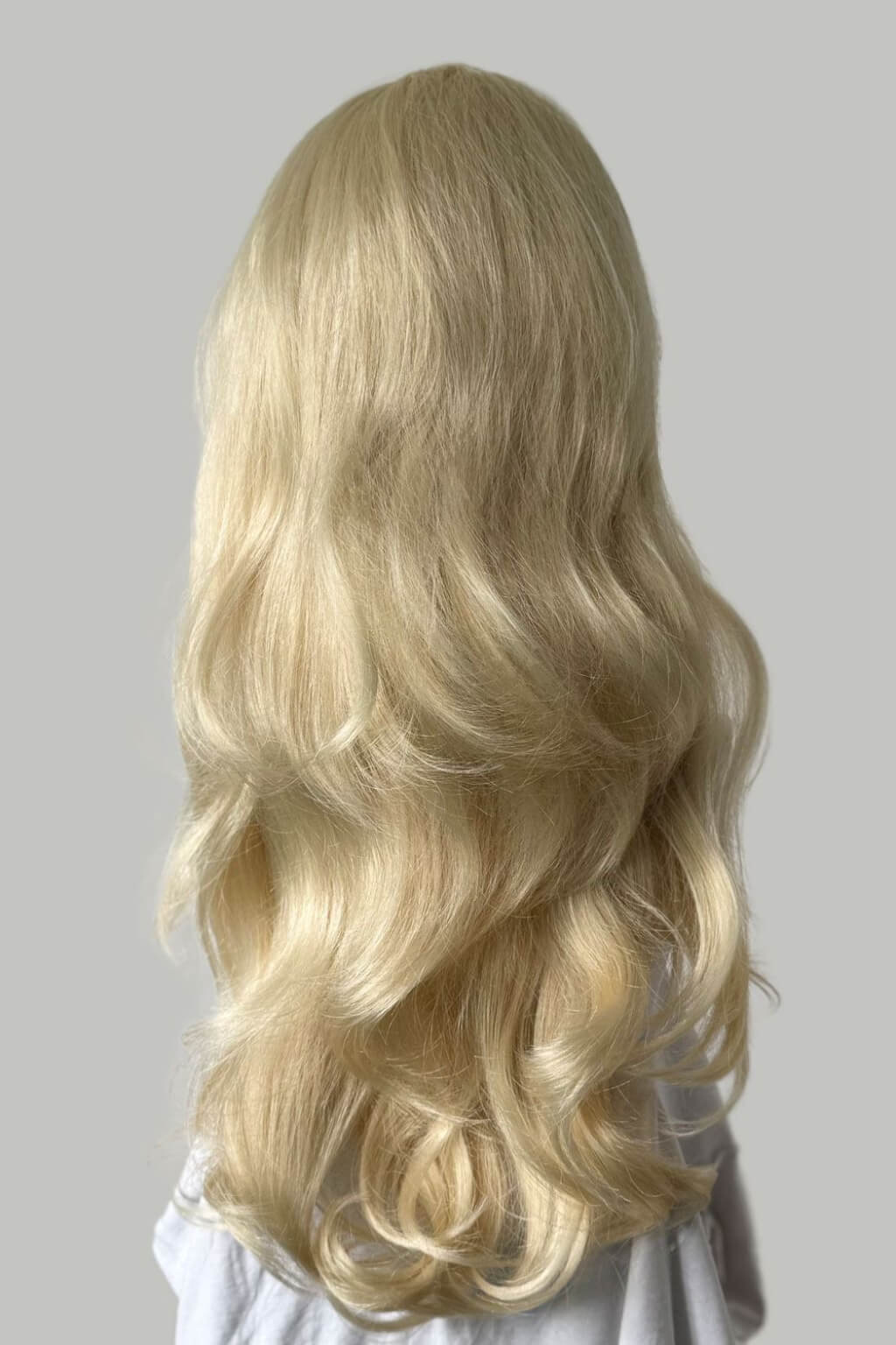 Blonde wig on a mannequin head against a plain background. Blonde half wig hairpiece (3/4 wig), loose curls: Suki creamy blonde 613