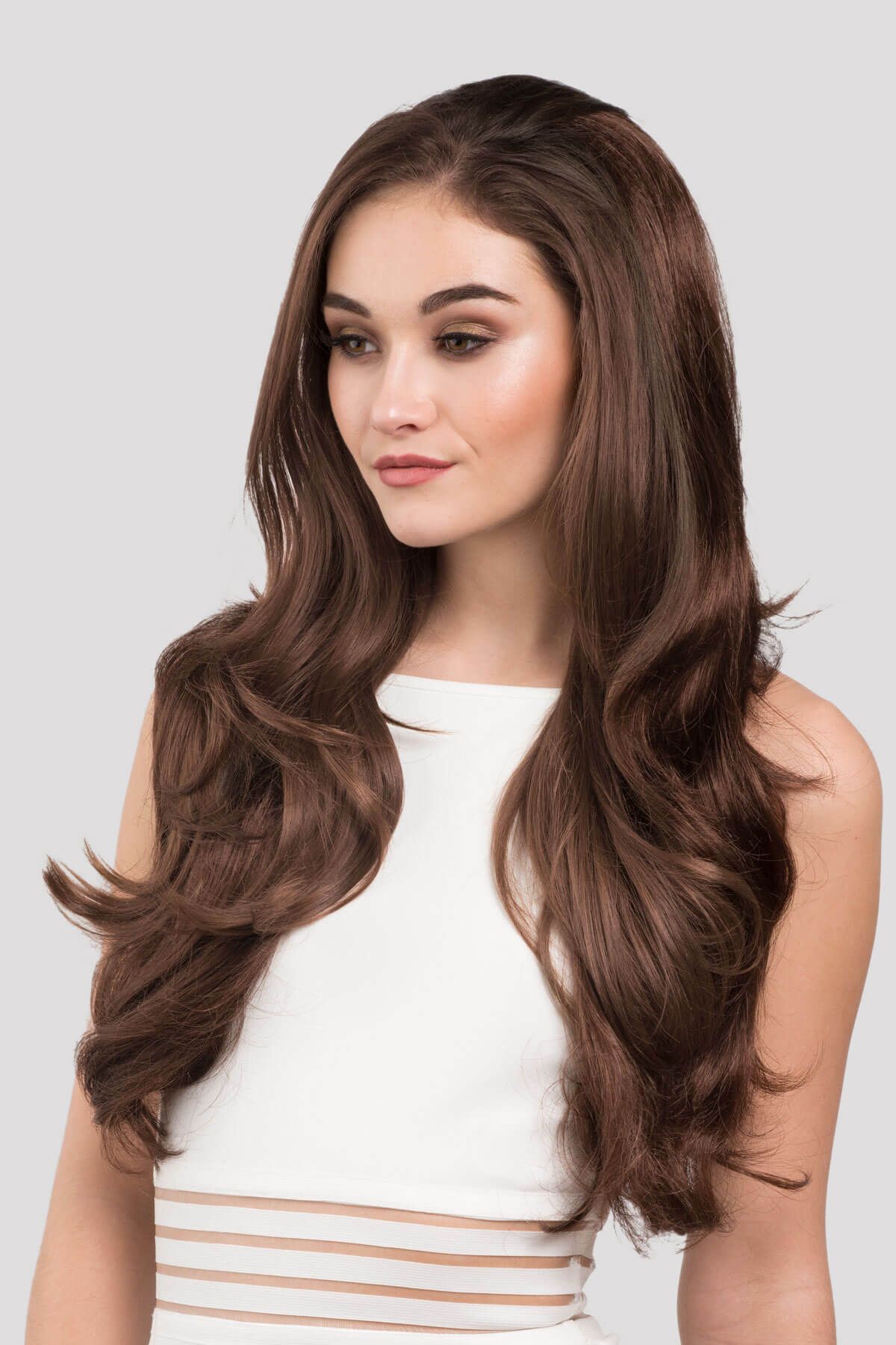 Woman with long, wavy brown hair wearing a white top against a light gray background. Reddish-brown half wig hairpiece (3/4 wig) with big loose curls: Anne