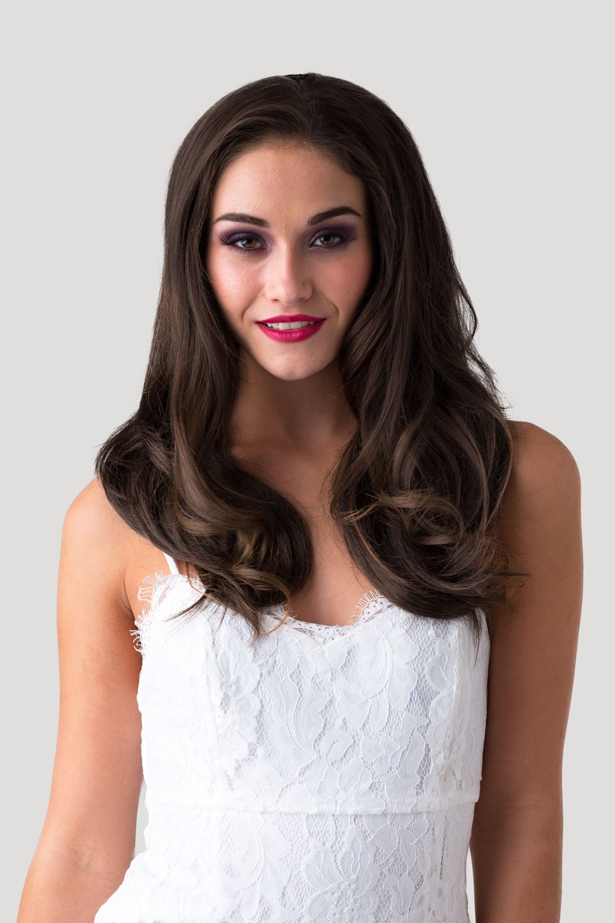 Woman with long dark hair wearing a white lace dress against a light gray background. Brown half wig hairpiece (3/4 wig), gently layered: Briar chestnut brown 8