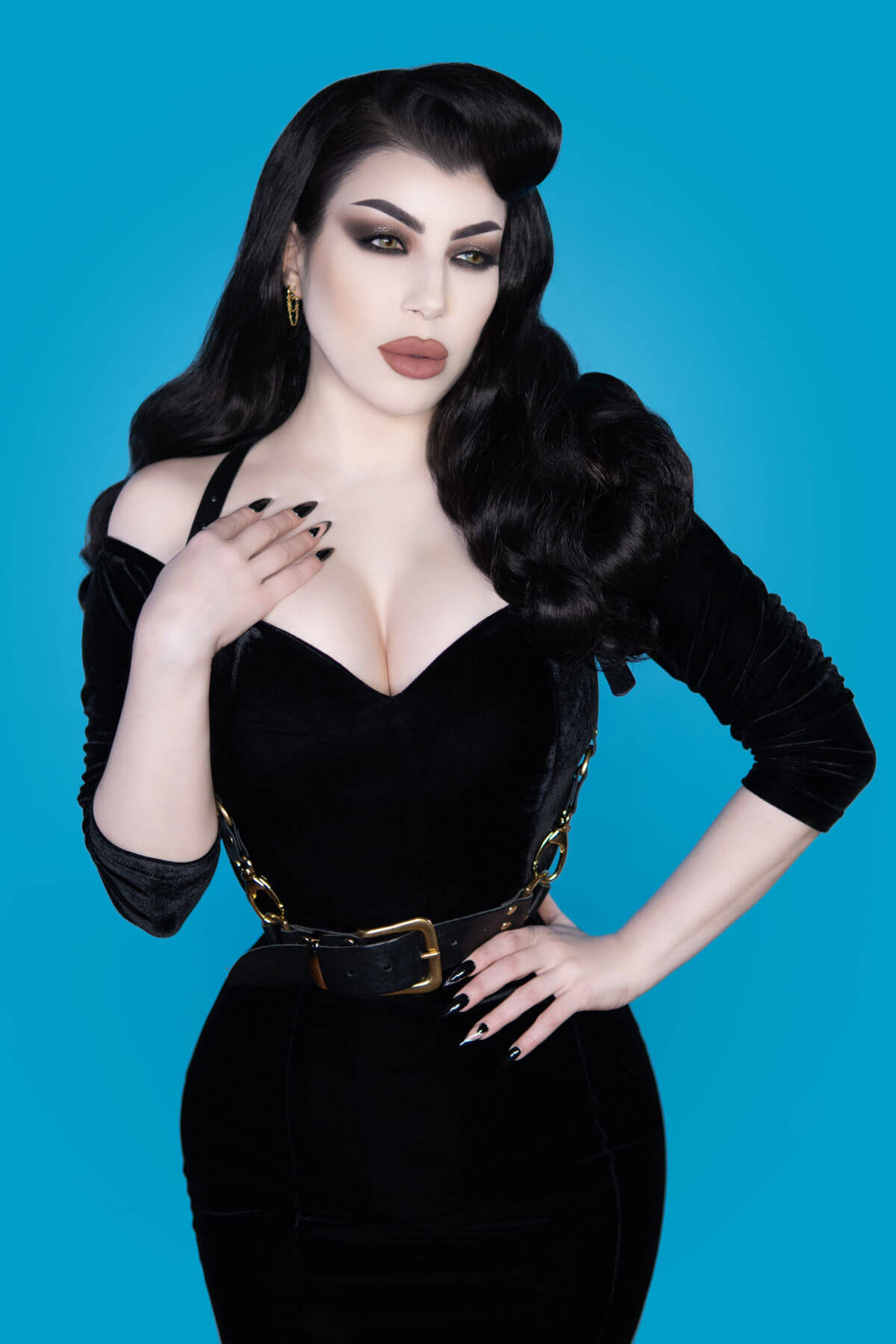 A woman wearing a 1950s style black dress with a half wig hairpiece featuring vintage waves.