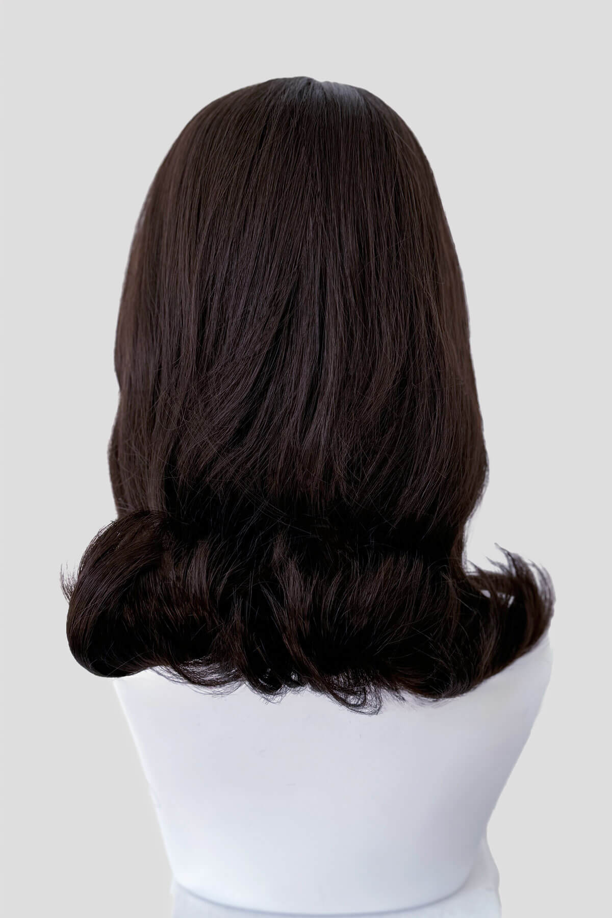 Dark brown wig on a mannequin head against a plain background. 1960s half wig hairpiece, flicked, hair flip: Philippa dark chocolate brown 6