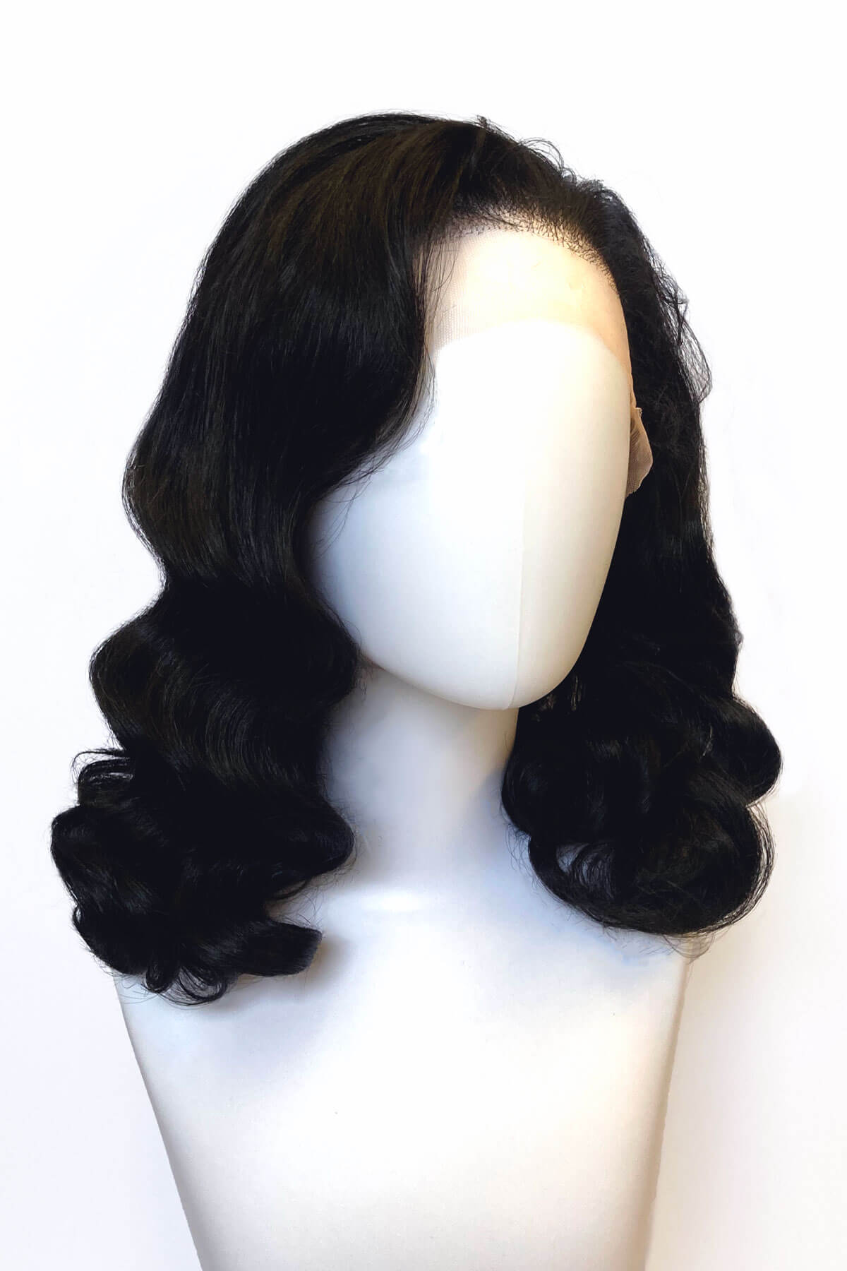 Black wavy wig on a mannequin head against a white background. Black pinup wig, lace front with long finger waves: Tyra