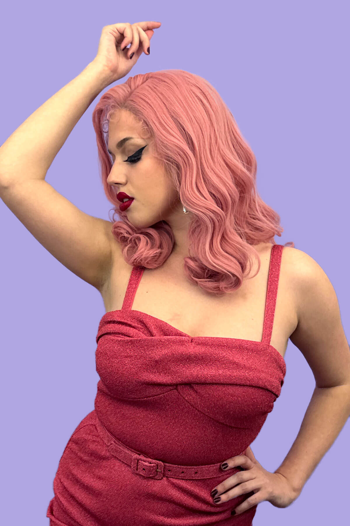 Woman with pink hair wearing a red dress against a purple background. Pink pinup wig, lace front, vintage style: Catalina