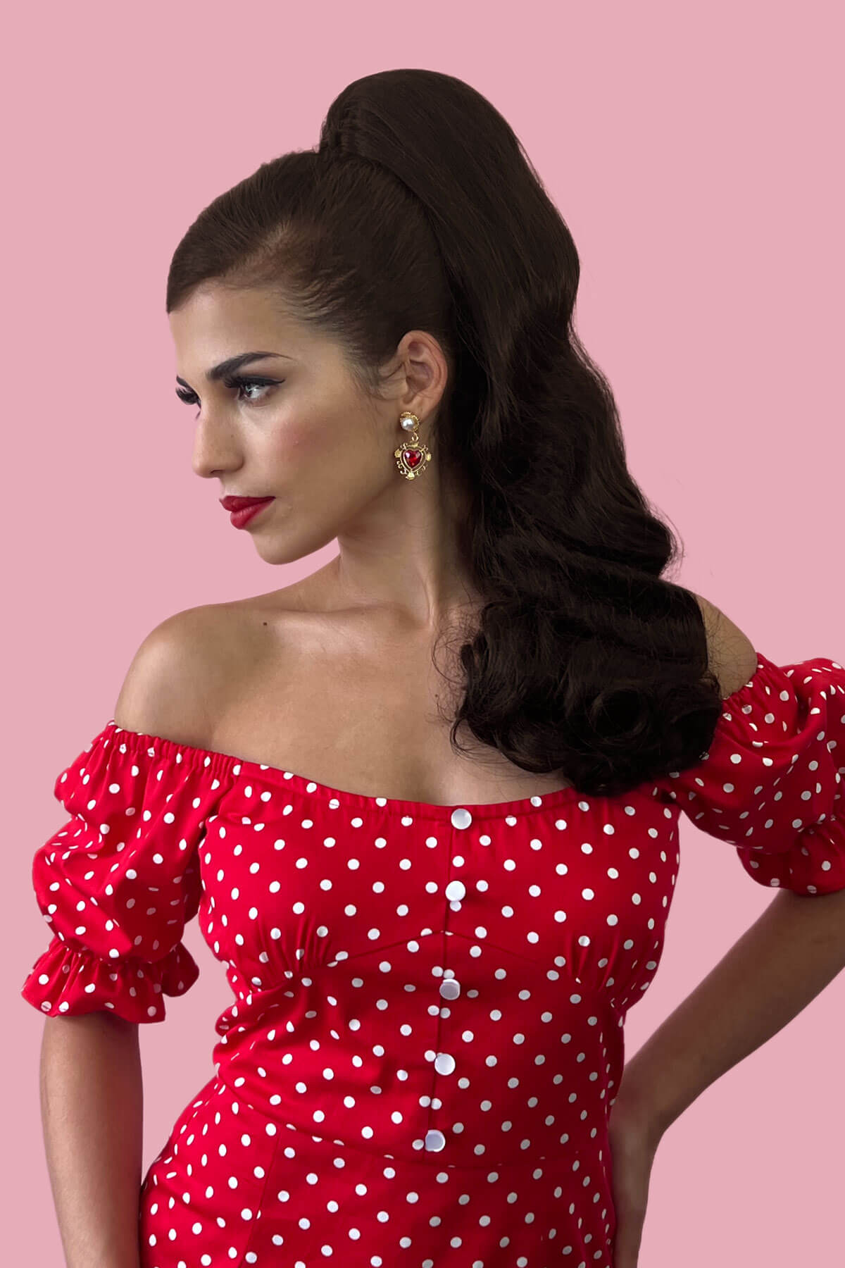 Woman wearing a red polka dot dress against a pink background. Retro style ponytail hairpiece, long with vintage waves: Arabella chestnut brown 8