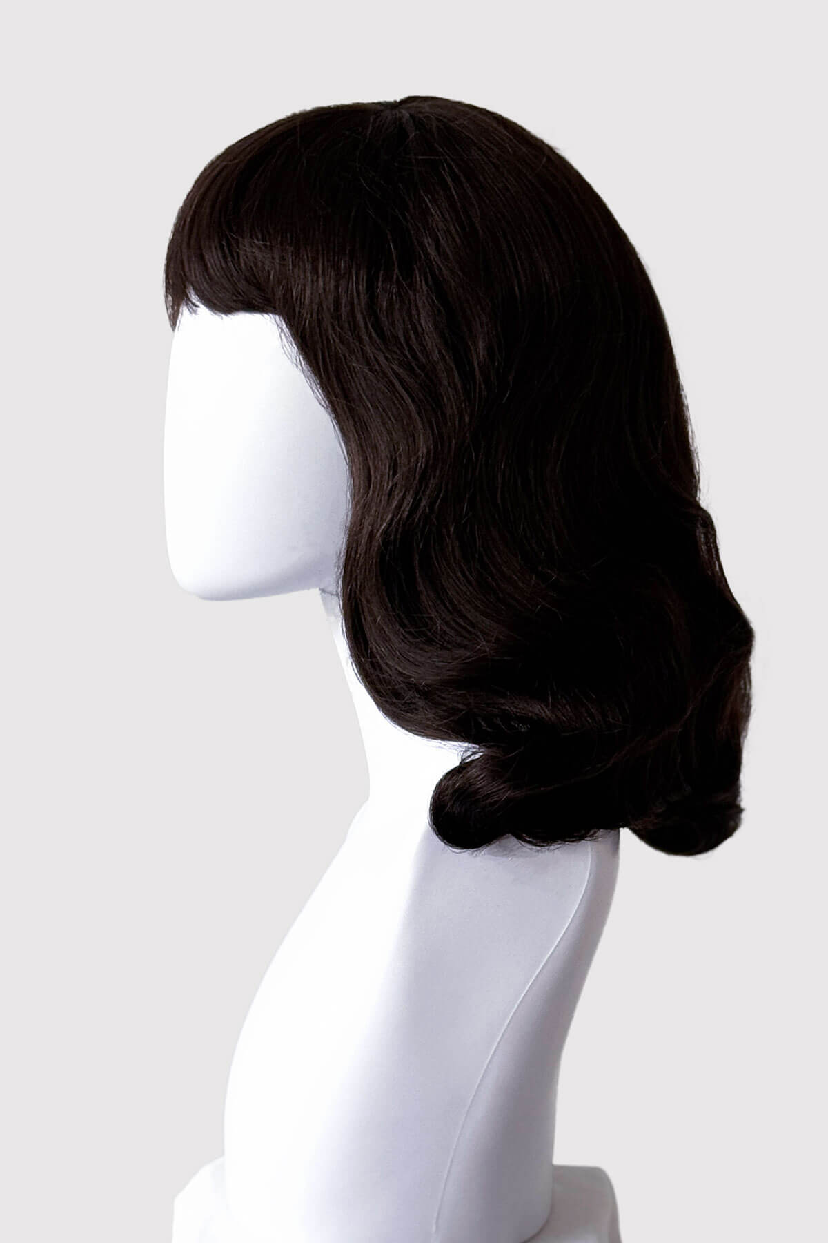 Dark brown wig on a mannequin head against a white background. Dark brown pinup style wig, finger waved with short fringe, 1950s style: Becca
