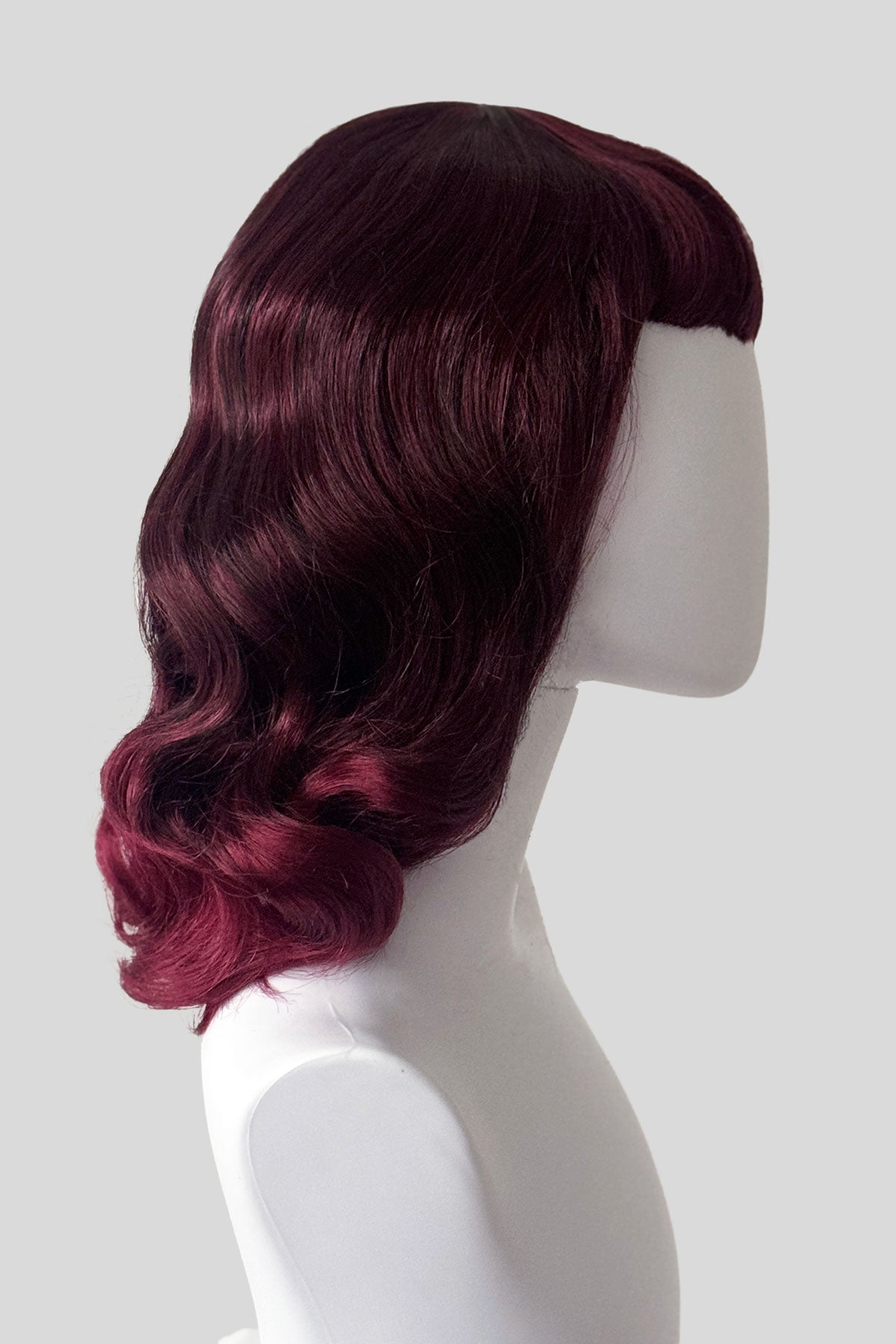 Mannequin head with a black and red wig on a white background. Black and red pin-up style wig, gently wavy with short fringe: Lillian