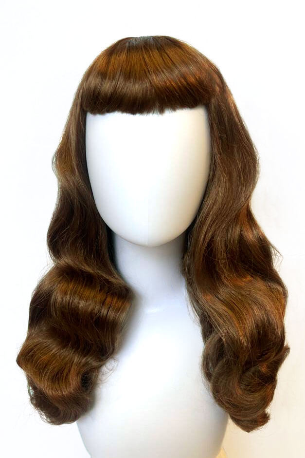 Brown wig on a mannequin head against a white background. Brown 1950s pinup style wig, with long waves and a short fringe: Rosie golden brown 12-27