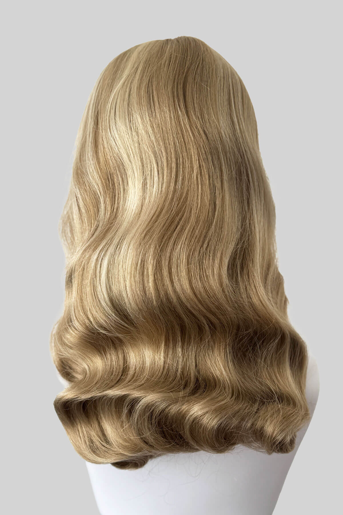Blonde wig on a mannequin head against a grey background. Long blonde pin-up wig, old Hollywood waves with short fringe: Emmeline