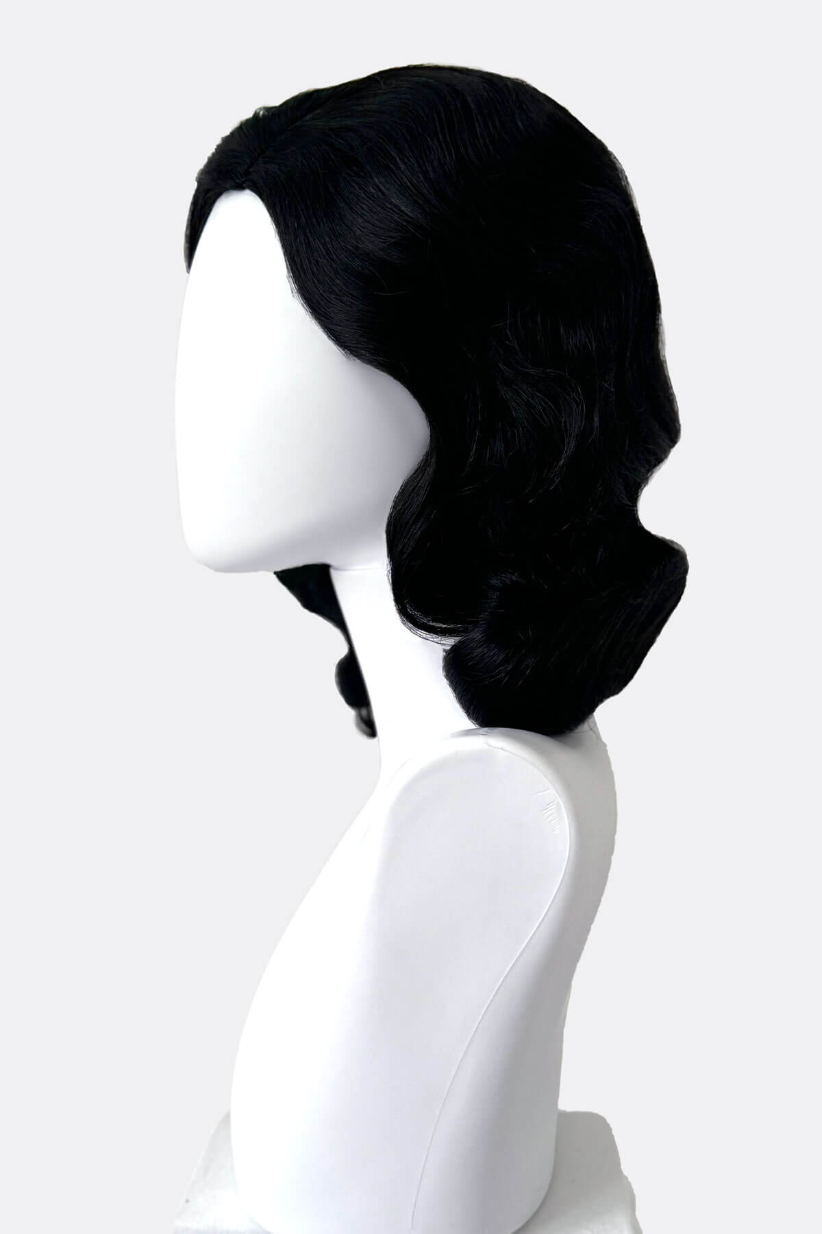 Black wig on a white mannequin head against a white background. Black 40s style wig with beautiful marcel waves: Dita