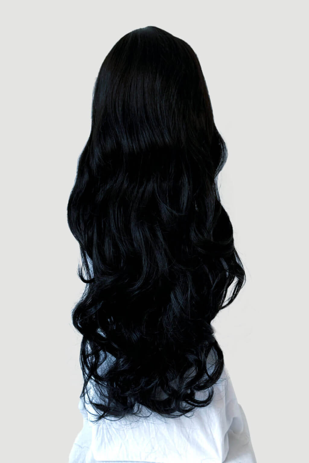 Long, black hair styled in loose waves on a plain background. Long wavy black wig with side-sweeping Fringe: Charlotte