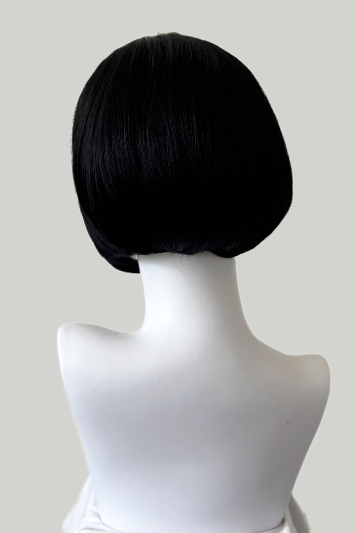 Black wig on a mannequin head from the back against a white background. Bob half wig hairpiece, Flexihair: Amelie black 1b