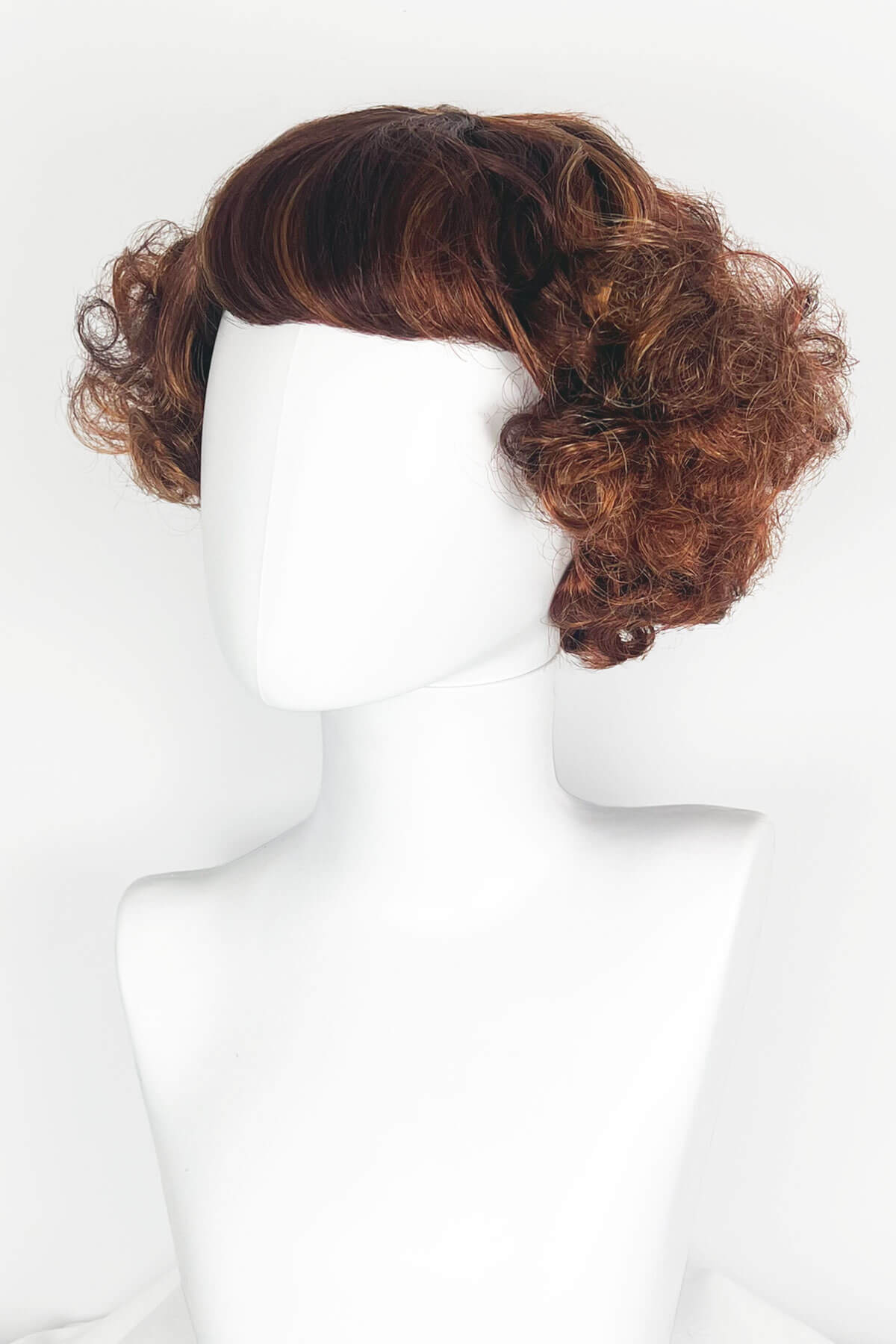 Brown wig on a mannequin head against a white background. A short red, auburn and blonde mix vintage style wig with waves: Solana Auburn BO