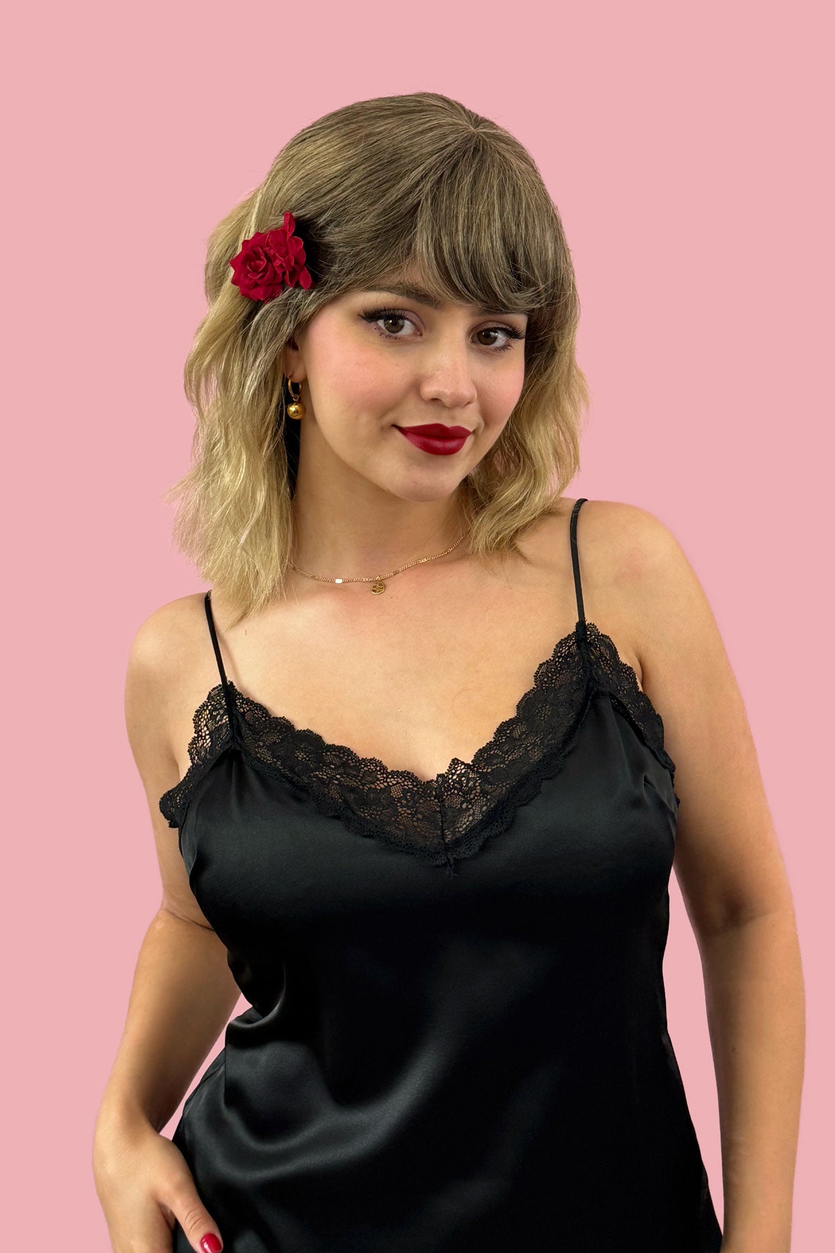 Woman wearing a black lace nightgown against a pink background. Long bob wig (LOB) with textured waves, blended from chestnut brown to blonde: Lili