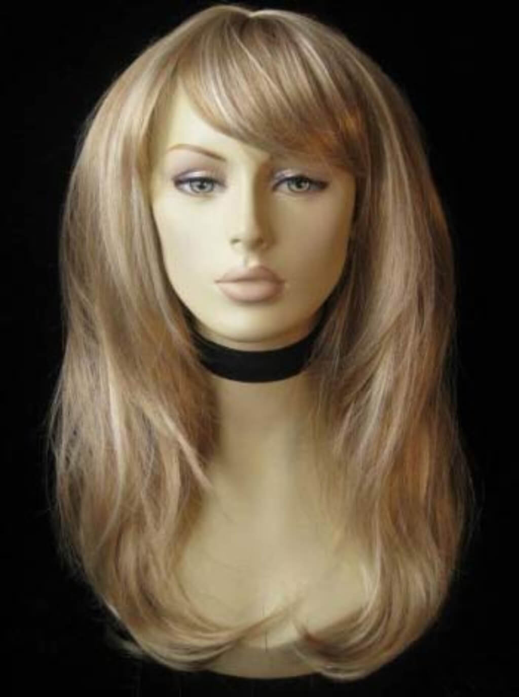 Blonde wig on a mannequin head against a black background. Long blonde wig, face framing with long, side-sweeping fringe: Ashley