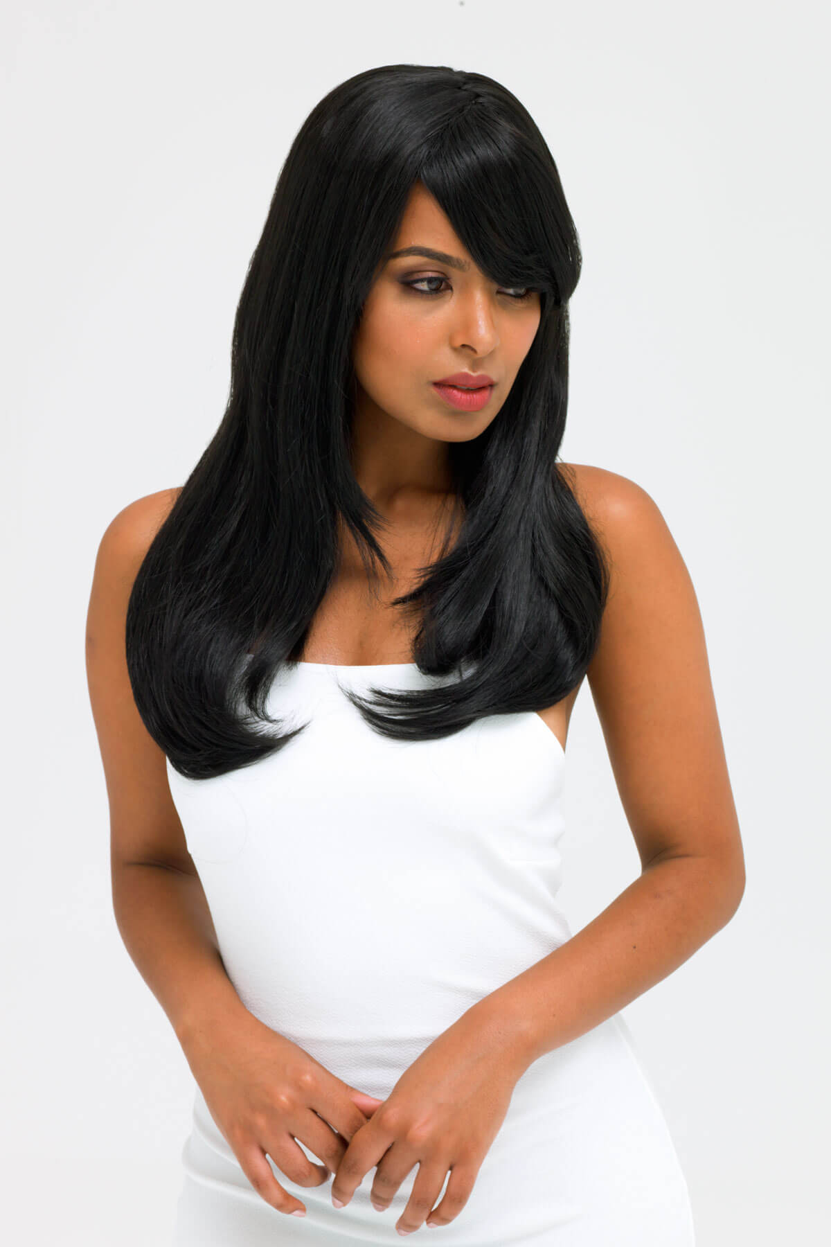 Woman with long black hair wearing a white dress on a plain background. Long black wig, face frame style with full, sweeping fringe: Corina
