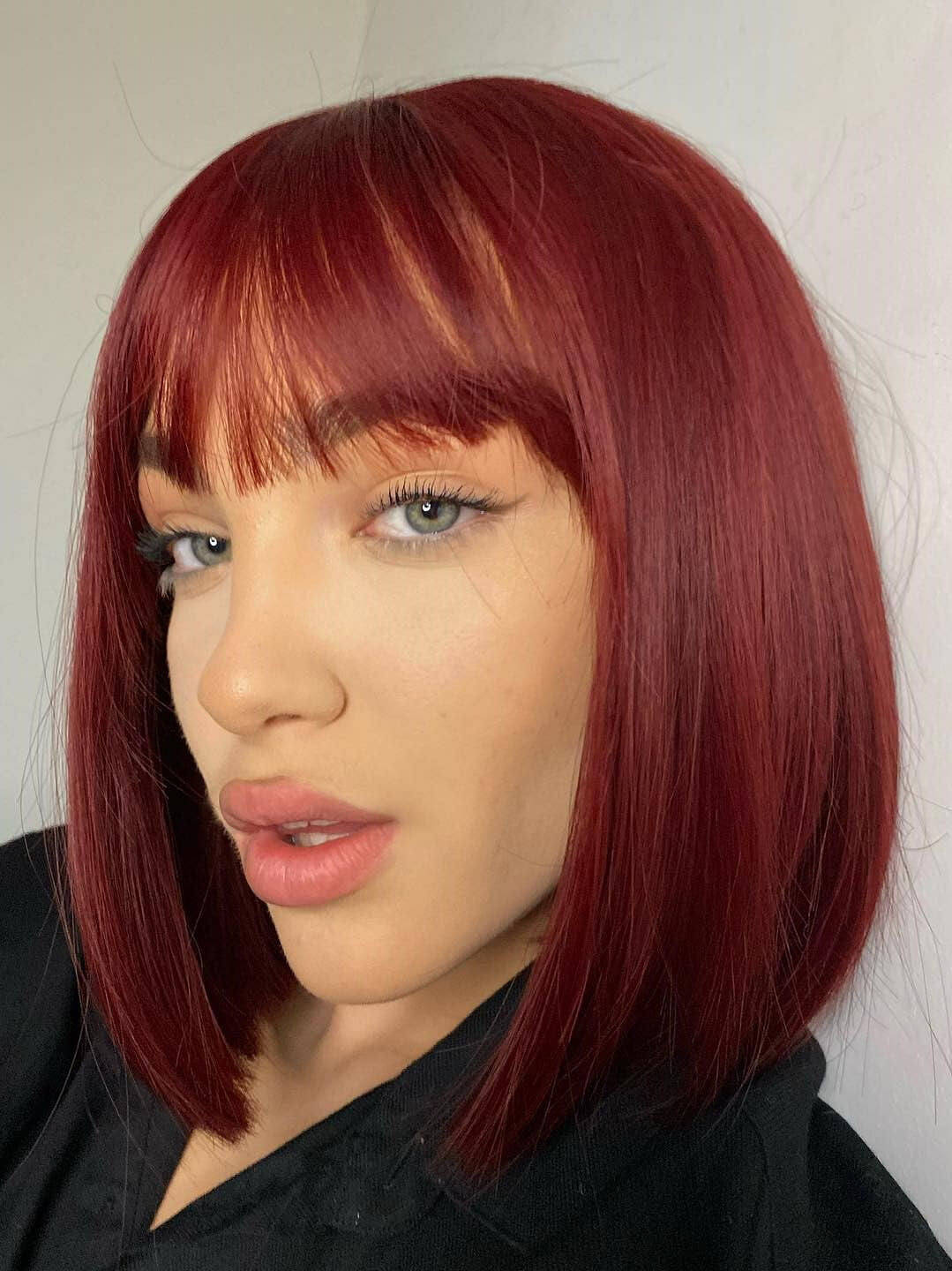 Person with red hair and a black top against a white background. Red inverted bob wig Red inverted bob wig, short and chic: Flavia