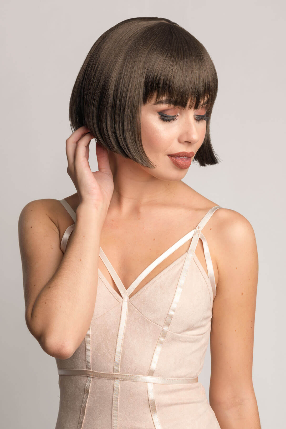 Woman with a stylish haircut wearing a beige dress against a plain background. Brown bob wig, chic and stylish: Honour chestnut brown 8
