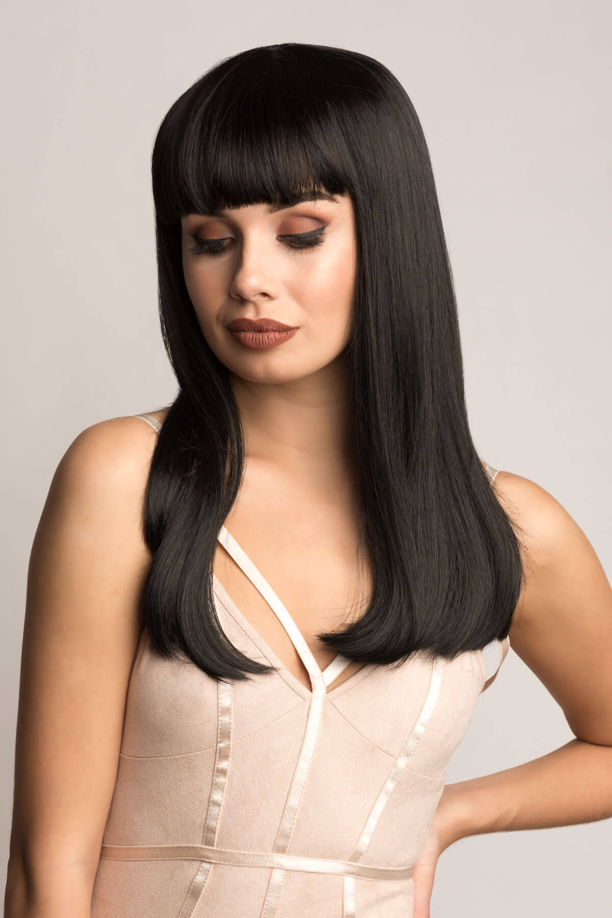 Woman with a straight black wig on a plain background. Long straight black wig with straight fringe: Carmen